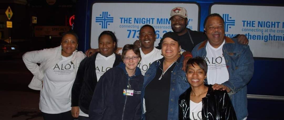 A group of people standing in front of a sign.