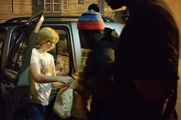 A man handing something to another person in the back of a van.
