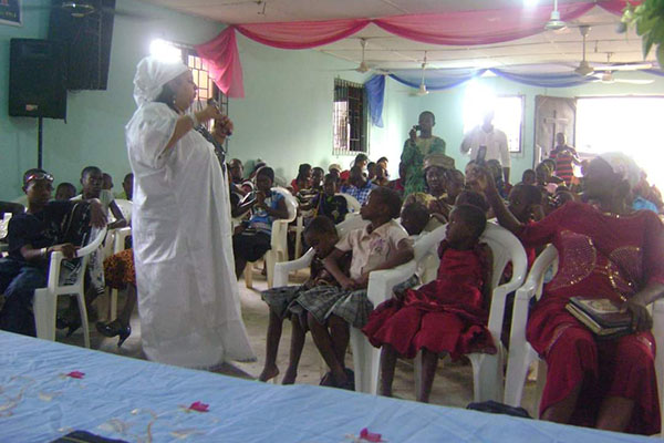 A woman in white is speaking to children.